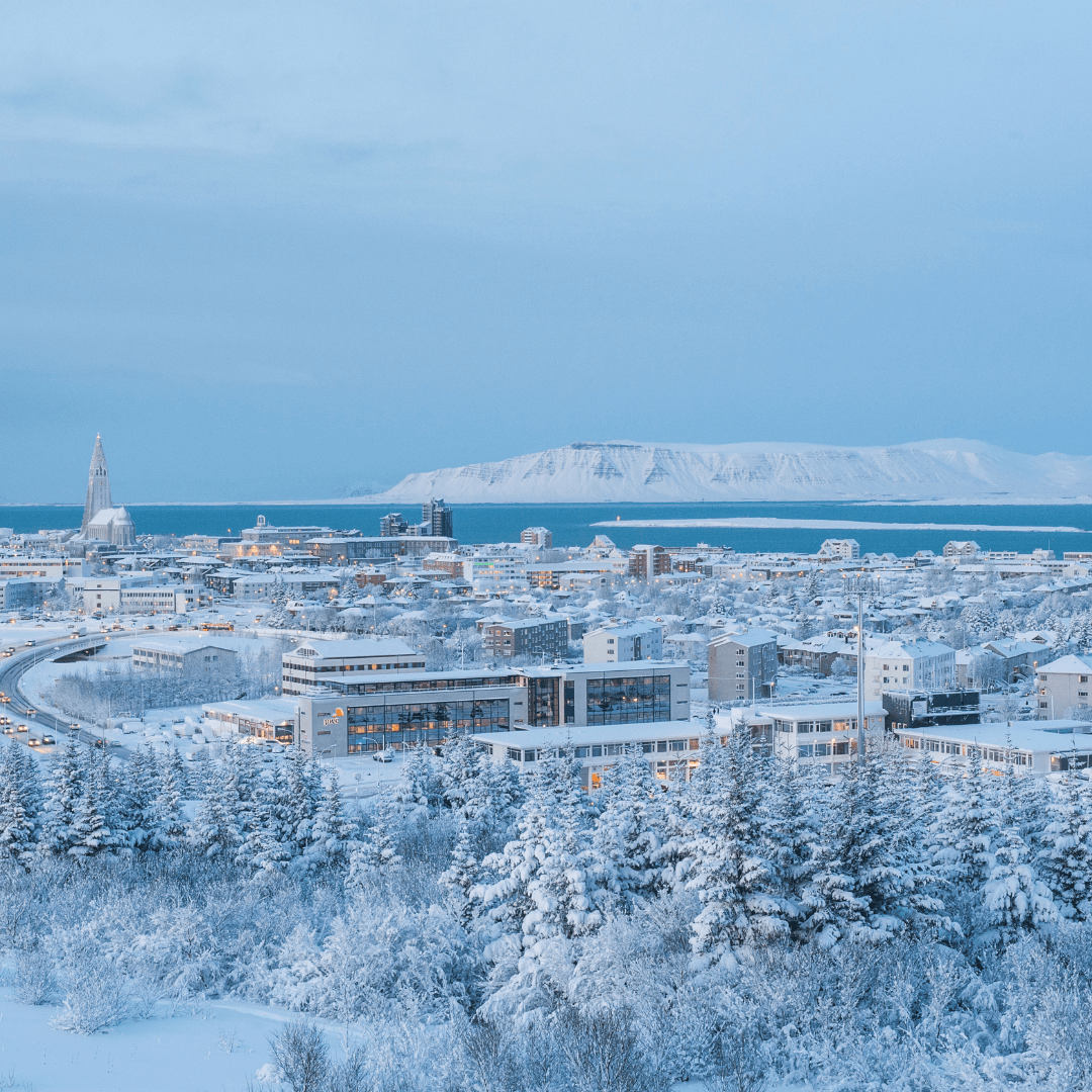 Snow-covered streets with colorful buildings and a winter sky in Reykjavik, Iceland.
