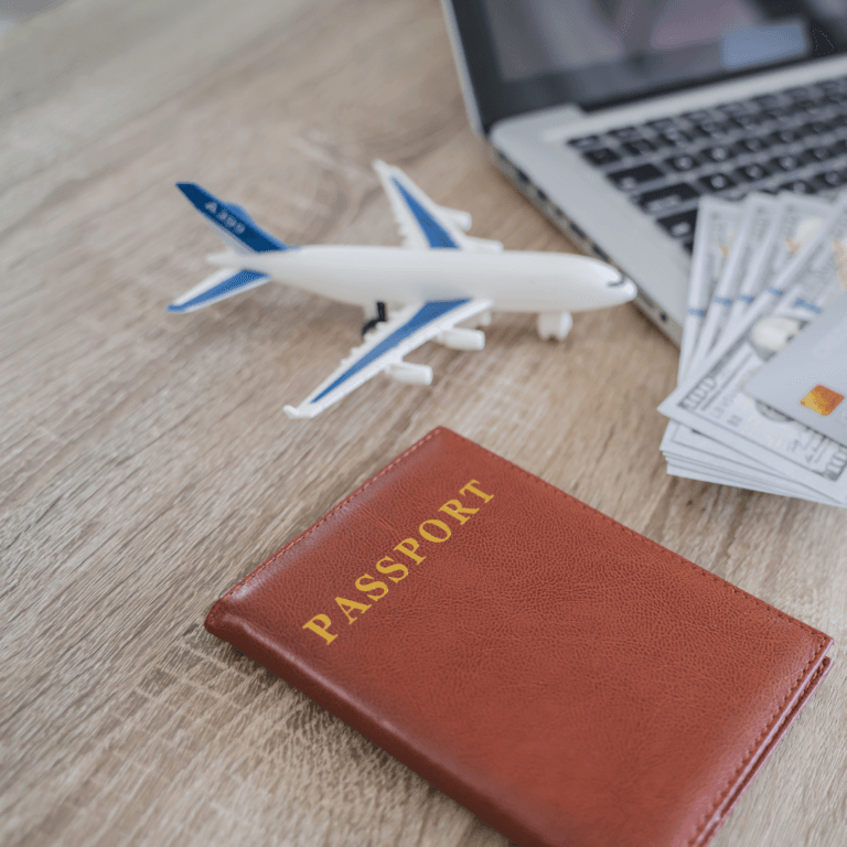 A brown passport with gold lettering placed on a wooden table, alongside a small airplane model, with a credit card. luxury travel on a Budget