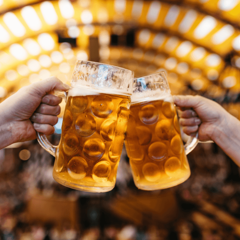 Two beers clinking together at Oktoberfest festival in Munich, celebrating Bavarian beer tradition.